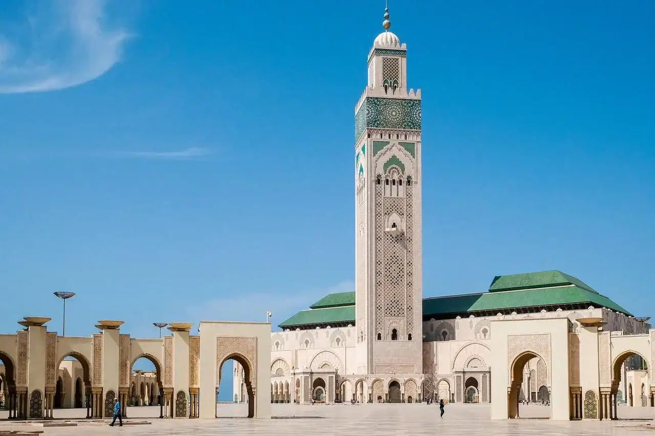 vue sous les arcades extérieures portique dune grande mosquée avec des colonnes ornées des arches festonnées et un sol en pavement poli reflétant la lumière