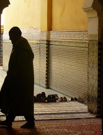 silhouette dun homme marchant sous une arche mauresque avec des mosaïques en zellige au maroc