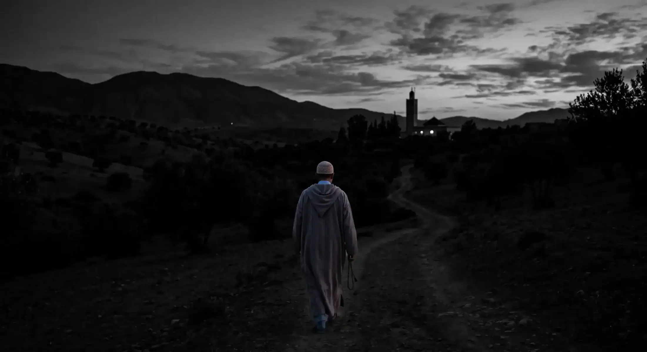 silhouette dun homme marchant vers une mosquée à laube pour la prière du fajr sous un ciel aux teintes orangées et violettes