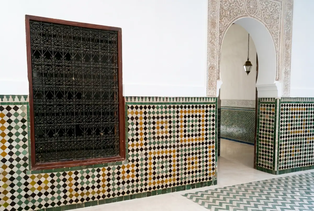 Vue d'ensemble de la cour du mausolée du Cadi Ayyad à Marrakech, montrant l'architecture des arcades, les lustres et les détails du plafond sculpté.
