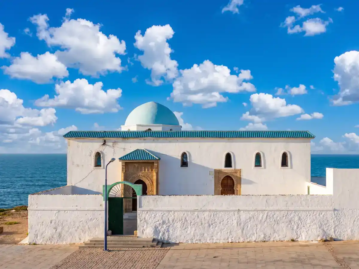 Entrée du mausolée de Sidi Moussa Doukkali à Salé, avec son dôme blanc (koubba), ses murs traditionnels et une porte en bois entourée de zelliges.