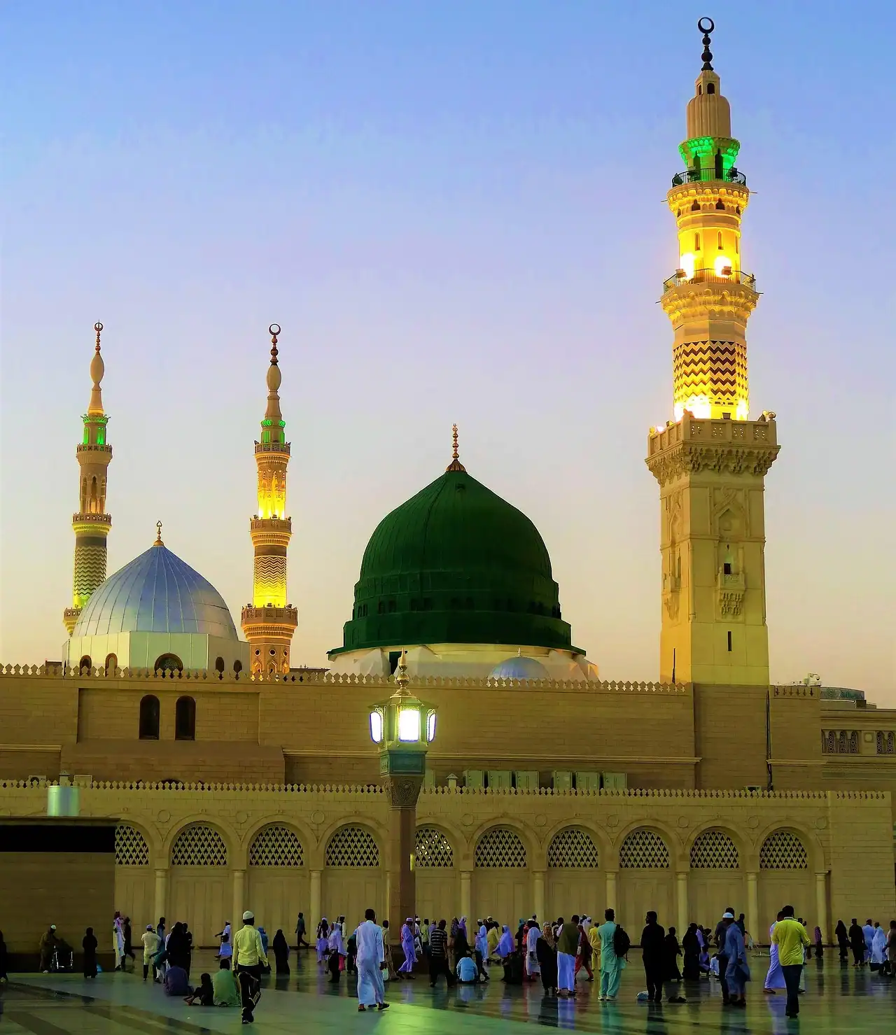 Vue de la mosquée Al-Masjid an-Nabawi à Médine avec son Dôme Vert et ses minarets illuminés au crépuscule.