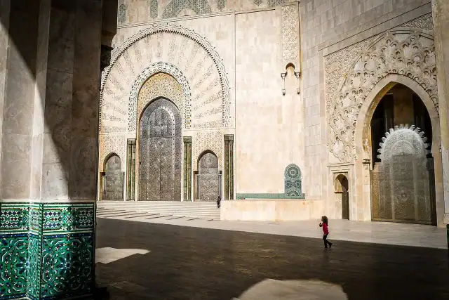 Esplanade de la Mosquée Hassan II à Casablanca montrant les grandes portes en titane ciselé et les façades en marbre avec mosaïques zellige.