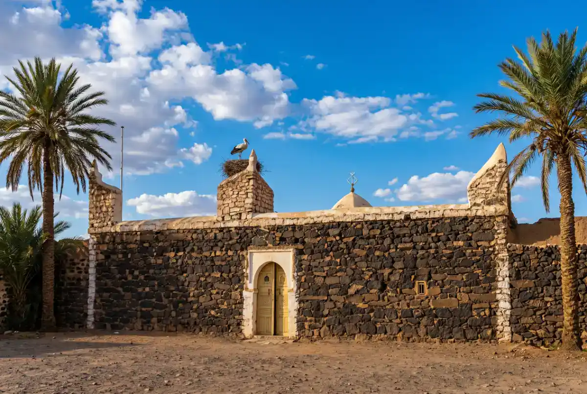 Entrée principale de la Zaouïa de Cheikh Ma El Aïnin à Tiznit, avec ses murs ocre, son portail traditionnel et son minaret en arrière-plan.